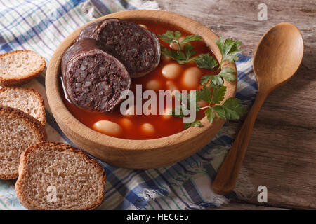 Una deliziosa minestra di fagioli Fabada asturiana closeup in una ciotola di legno orizzontale. Foto Stock