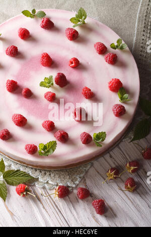 Rosa lampone cheese cake con la menta e frutti di bosco freschi vicino sul tavolo. verticale vista superiore Foto Stock