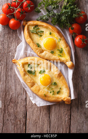 Due khachapuri georgiano e ortaggi freschi sul tavolo. verticale vista superiore Foto Stock