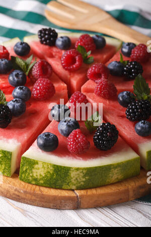 Pizza di frutta anguria con frutti di bosco freschi e menta close-up verticale. Foto Stock