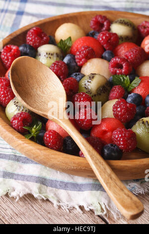 Insalata di frutta di mirtilli, anguria, lampone, melone e kiwi in ciotola di legno closeup. In verticale Foto Stock