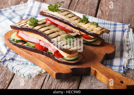 Sandwich di melanzane con verdure fresche, prosciutto e formaggio sulla tavola orizzontale. Foto Stock