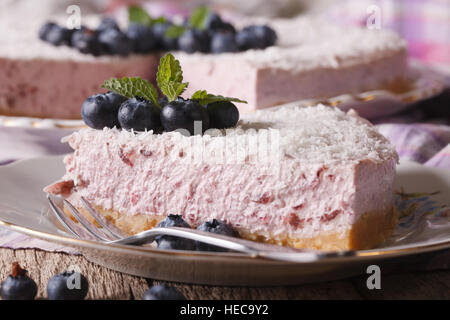 Un pezzo di deliziose mirtillo cheesecake con frutti di bosco freschi e macro di cocco su una piastra orizzontale. Foto Stock