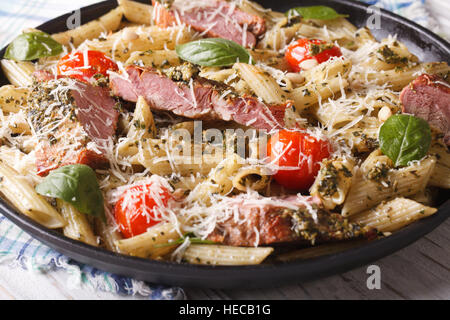 Penne pasta con carne, parmigiano e pesto close up su una piastra orizzontale. Foto Stock