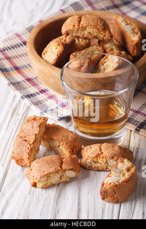 Italiana mandorla biscotti biscotti e vino dolce in un bicchiere sulla tavola verticale. Foto Stock