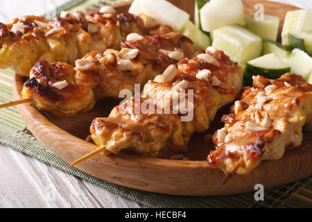 Kebab asiatici: Pollo satay cosparso con arachidi tostate close-up su una piastra orizzontale. Foto Stock