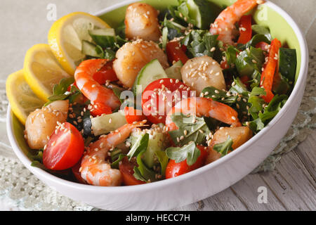 Insalata fresca con gamberetti, capesante e verdure vicino fino in una ciotola sul tavolo orizzontale. Foto Stock