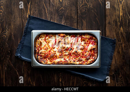 Il cibo italiano. Hot gustose lasagne in ceramica casseruola sul tavolo di legno Foto Stock