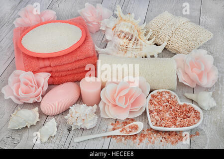 Pulizia Accessori spa con sale himalayano, rose petali di sapone esfoliante e prodotti per bagno su distressed bianco sullo sfondo di legno. Foto Stock