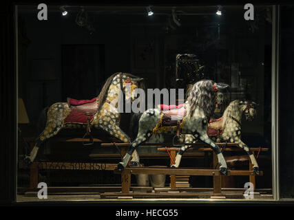 In legno Vintage cavalli a dondolo in un negozio di antiquariato finestra la notte. Tetbury, Gloucestershire, Inghilterra Foto Stock