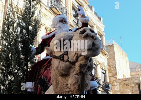 Gerusalemme, Israele. Xx Dicembre, 2016. Santa Claus, o "Baba Noel' come egli è chiamato nel locale di lingua araba, emerge dal Patriarca Latino strada in Gerusalemme la città vecchia di cavalcare un cammello sostituendo per la pioggia di cervo. Il comune di Gerusalemme e quella ebraica del fondo nazionale distribuiti appositamente coltivate Cipro Cedar alberi di Natale alla popolazione cristiana presso la Porta di Jaffa. Credito: Nir Alon/Alamy Live News Foto Stock