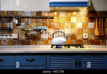 Nuovo metallo sibilo bollitore ebollizione in cucina. La cucina moderna è blu. Foto Stock