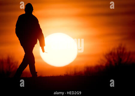 Hannover, Germania. Xxi Dec, 2016. Meteo. Un uomo passeggiando su un percorso di campo come il sole tramonta sull'orizzonte il 21 dicembre 2016 - il giorno più corto dell'anno - vicino ad Hannover in Germania. Dal 21 dicembre, il solstizio d'inverno, le notti saranno iniziano ad accorciarsi e i giorni diventerà più lungo. Credito: dpa picture alliance/Alamy Live News Foto Stock