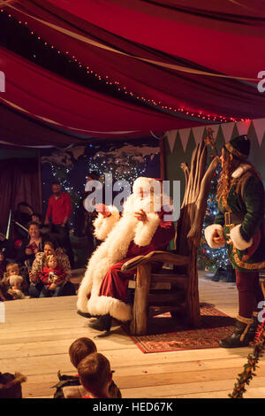 Babbo Natale noto anche come Santa Claus per intrattenere i bambini e i genitori con gli elfi aiutanti e. Scena festiva Foto Stock