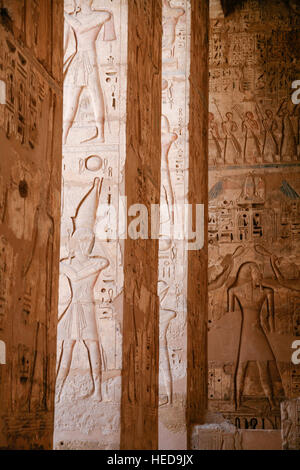 Dipinti egiziani, carving figure e geroglifici in colonne e una parete di pietra miliare tempio di Ramses o Ramesse III a Medinet Habu, monumento in Luxo Foto Stock