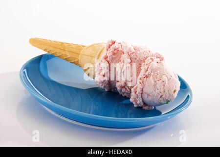 Cono gelato riempito con palline di gelato alla fragola che giace su di una piastra Foto Stock