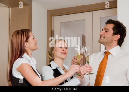 Tre giovani imprenditori con vino frizzante occhiali, tostatura, bicchieri tintinnanti Foto Stock