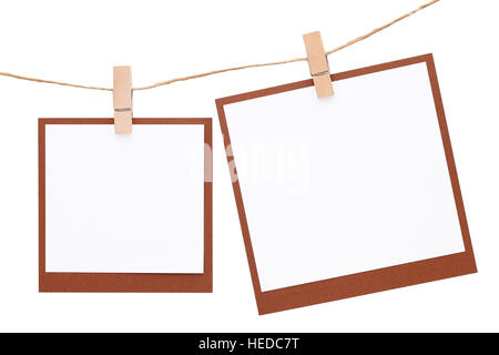 Blank Foto istantanea appeso sulla corda con clothespin isolati su sfondo bianco Foto Stock