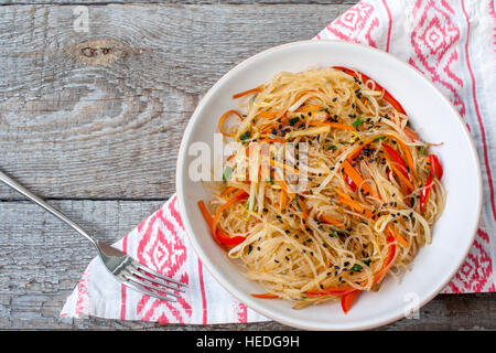 Spaghetti di riso con verdura stir fry sul vaso di ceramica su legno scuro dello sfondo Foto Stock