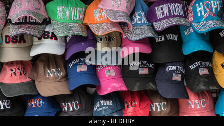 I cappelli da baseball con simboli celebra la città di New York sono stati appesi in una salda formazione disponibile per la vendita su strada. Foto Stock