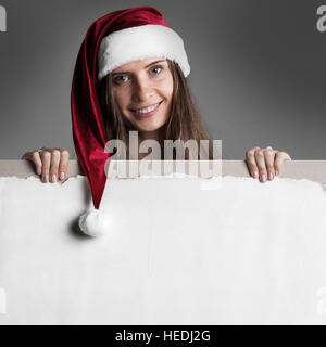 Felice donna sorridente in Santa il suo cappello bianco con intestazione vuota con lo spazio di copia Foto Stock