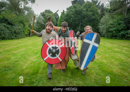 Aberystwyth studente universitario società - Historica Normannis (un secolo XII rievocazione storica gruppo, concentrandosi in particolare sugli eventi tra il regno di Enrico I e Re Giovanni.) - tre persone in carica e agitando le loro spade Foto Stock