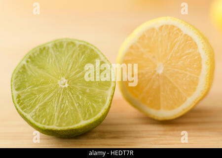 Le due metà a fette di limone e calce su un tagliere. Foto Stock