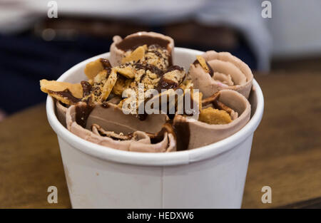 Close up di gelato al cioccolato rotoli laminati (gelato) in un bicchiere di carta con salsa di cioccolato e wafer spruzzino, STATI UNITI D'AMERICA Foto Stock