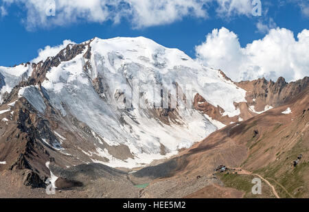 Grandiosa vista del picco di neve sullo sfondo del cielo blu con nuvole. Il Lago Moraine e il campo base sono al piede della montagna. Tian Shan m Foto Stock