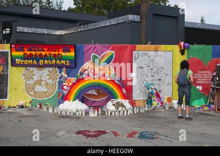 Un passerby smette di leggere omaggi a sinistra un memoriale di fortuna intorno al nightclub di impulsi 18 Dicembre 2016 a Orlando, Florida. Il 12 Giugno 2016 49 persone sono state uccise e 53 ferite in più letali riprese di massa mediante un unico pistolero nella storia degli Stati Uniti e più letali attacchi terroristici sul suolo americano dopo gli eventi dell'11 settembre 2001. Foto Stock