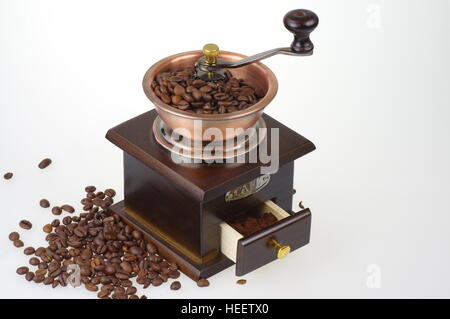 Old-style manuale caffè macinacaffè sullo sfondo bianco. Intorno al mulino sono sparsi i chicchi di caffè. Foto Stock