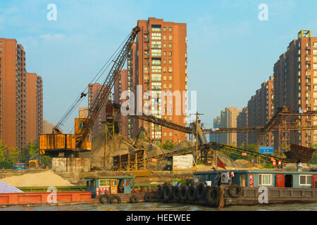 Chiatte a banchina di carico sul Canal Grande, moderna città lungo la riva del fiume, Hangzhou, nella provincia di Zhejiang, Cina Foto Stock