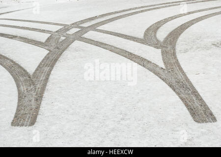 Tracce di pneumatici / iscrizioni in neve fresca su una strada asfaltata. Foto Stock