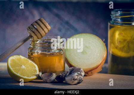 Le medicine naturali contro la canna fumaria e freddo. Il miele, limone, tè caldo, cipolla e aglio. Concetto di salute. Foto Stock