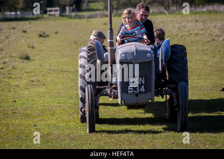 Un'annata del trattore su una fattoria Kent essendo azionato da un papà con sua figlia sul suo giro, Kent, Inghilterra, Regno Unito. Foto Stock