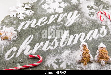 Auguri di Buon Natale e scritto con lo zucchero in polvere e i cookie di vacanza Foto Stock