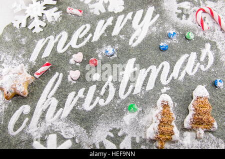 Auguri di Buon Natale e scritto con lo zucchero in polvere e i cookie di vacanza Foto Stock