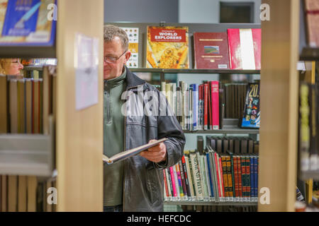 L'uomo la lettura di un libro alla libreria Kopavogur, Kopavogur, Islanda Foto Stock