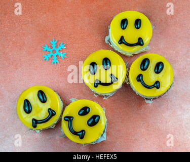 Cinque giallo cheesecake decorate con sorrisi facce con i fiocchi di neve Foto Stock