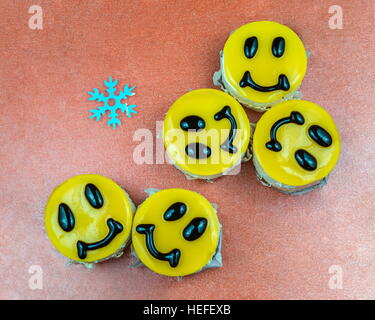 Cinque giallo cheesecake decorate con sorrisi facce con i fiocchi di neve Foto Stock
