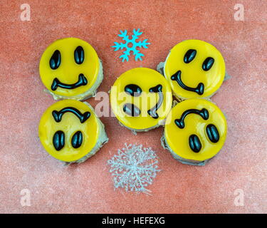 Cinque giallo cheesecake decorate con sorrisi facce con due fiocchi di neve Foto Stock