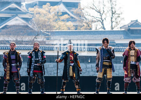 Yosakoi giapponese festival. Danzatori vestiti come il samurai warriors, esecuzione di breve mostra sul palco con il Castello di Kumamoto in background. Foto Stock