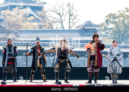 Yosakoi giapponese festival. Danzatori vestiti come il samurai warriors, esecuzione di breve mostra sul palco con il Castello di Kumamoto in background. Foto Stock