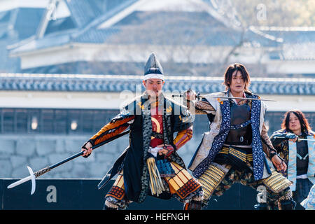 Yosakoi giapponese festival. Danzatori vestiti come il samurai warriors, esecuzione di breve mostra sul palco con il Castello di Kumamoto in background. Foto Stock