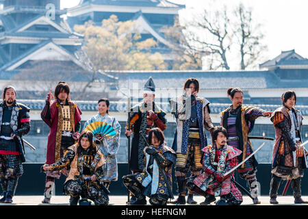 Yosakoi giapponese festival. Danzatori vestiti come il samurai warriors, esecuzione di breve mostra sul palco con il Castello di Kumamoto in background. Foto Stock