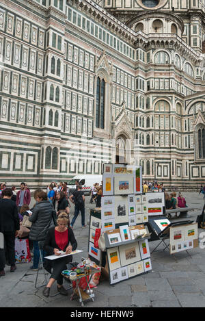 Donna con esposizione di pitture per la vendita di fronte al Duomo di Santa Maria del Fiore, Firenze, Toscana, Italia Foto Stock