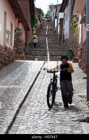 Un bambino su una bicicletta in una delle ripide stradine del piccolo villaggio di Chinchero nella Valle Sacra nei pressi di Cuzco. Chinchero è un piccolo indiano andina Foto Stock