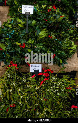 Holly ghirlande e vischio per la vendita a Natale Street Market, Lewes, Sussex, Regno Unito Foto Stock