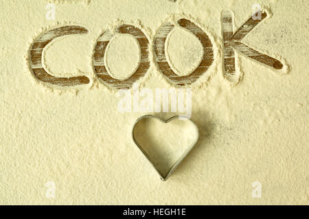 Farina a fontana sul tavolo con parola writted COOK Foto Stock