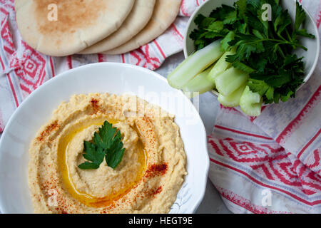 Home classic hummus con sedano, pita. Vista dall'alto sul cemento grigio Sfondo. Cibo Vegan concetto. Foto Stock